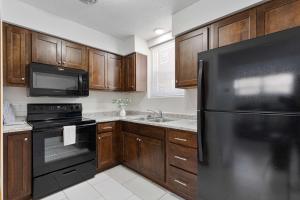 uma cozinha com armários de madeira e um frigorífico preto em Nadia's Place em Omaha