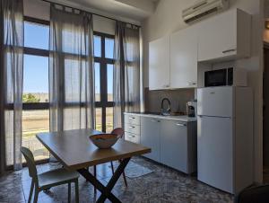 een keuken met een tafel en een witte koelkast bij Monolocale Viale Arbatax in Tortolì