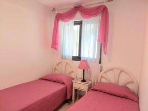 een slaapkamer met 2 bedden en een raam met roze lakens bij Lookatbeach in Oropesa del Mar