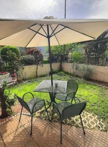 a table and chairs under an umbrella on a patio at La Civetta appartamento con giardino e parcheggio in Nave