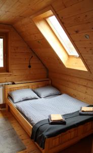 Bett in einer Holzhütte mit Fenster in der Unterkunft Štýlový Zrub Martina A s kúpacou Kaďou a detským ihriskom! in Ždiar