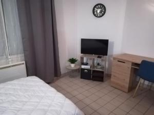 a bedroom with a bed and a desk with a television at Studio meublé 27 mètres carrés wifi netflix in Niort