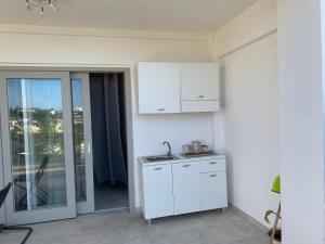 uma cozinha branca com um lavatório e uma porta para uma varanda em La caccetta em Procida
