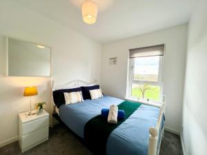 a bedroom with a blue bed and a window at Luxurious & Modern Apartment in Hawkhead