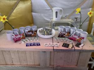 uma mesa coberta com copos e pacotes de doces em Vigo Retreat Yurt em Wrotham