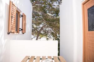 ein weißes Haus mit einem Fenster und einer Holzbank in der Unterkunft Fira Central Budget Room and Kitchen in Fira