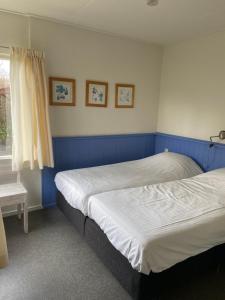 2 camas en un dormitorio con paredes azules y ventana en Rustig gelegen bungalow op Texel, en Oosterend