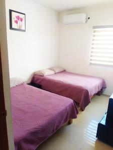 two beds in a room with purple sheets at Departamento Moderno Alberca Compartida - 6 Personas in Mazatlán