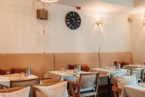 una sala da pranzo con tavoli e un orologio sul muro di Hotel La Riva a Siófok