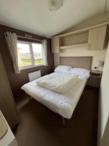 uma cama num pequeno quarto com uma janela em Ormesby 8, Haven Holiday Park, Caister - Four Bedroom, sleeps 8, pets welcome - 2 minutes from the beach! em Great Yarmouth