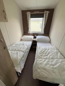 um quarto com três camas e uma janela em Ormesby 8, Haven Holiday Park, Caister - Four Bedroom, sleeps 8, pets welcome - 2 minutes from the beach! em Great Yarmouth