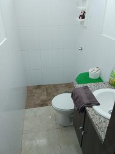 La salle de bains blanche est pourvue de toilettes et d'un lavabo. dans l'établissement Alojamiento y transporte, à Guayaquil