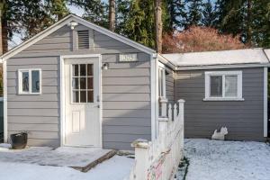 un pequeño cobertizo con una puerta blanca en la nieve en Adorable Cottage near Scenic Waterfront Park, en Everett