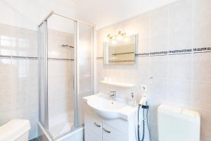 een witte badkamer met een wastafel en een douche bij Pension Wald und See in Ahlbeck