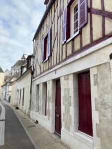 um edifício com portas vermelhas e janelas numa rua em L’Atelier cosy em Auxerre