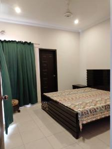 1 dormitorio con cama y cortinas verdes en Balqees Cottage en Lahore