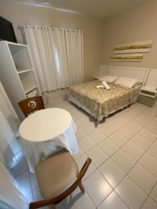 a bedroom with a bed and a table and a chair at Hotel Enseada in São Francisco do Sul