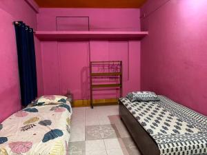 2 letti in una camera con pareti rosa di City Homestay a Guwahati