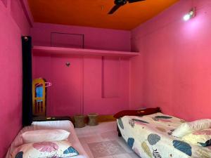 a bedroom with pink walls and two beds in it at City Homestay in Guwahati