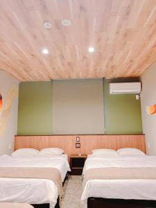 Habitación con 3 camas y pared verde. en ホテル　レヴィベース思案橋 en Nagasaki
