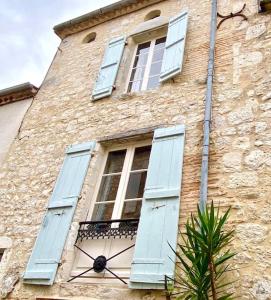 un edificio in pietra con persiane blu e finestra di Maison St. Clair a Monflanquin