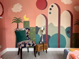 una camera con una sedia e una parete con un murale di Vibrant City Cottage in Camberwell a Londra