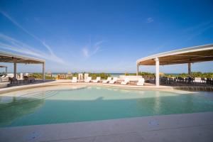 a large swimming pool with chairs and a view of the ocean at SIELA Oceanfront Luxury 4 BR Villa in San Bruno