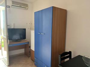 um armário azul ao lado de uma secretária com uma televisão em Amerigo Casa Vacanza em Cefalù