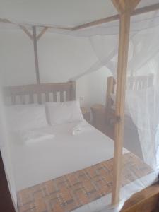 1 dormitorio con 1 cama blanca con dosel en Real African Life safaris and Camps, en Lukungu