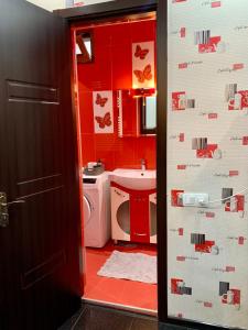 La salle de bains est pourvue de murs rouges, d'un lavabo et de toilettes. dans l'établissement Brothers, à Tbilissi