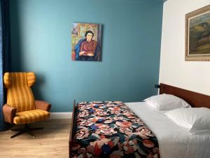 ein Schlafzimmer mit einem Bett, einem Stuhl und einem Gemälde in der Unterkunft Les Loges du Théâtre Monsigny, Centre-ville in Boulogne-sur-Mer