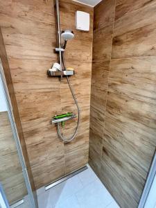 een douche in een badkamer met een houten muur bij Ruhig & Gemütlich Nahe Frankfurt in Neu Isenburg
