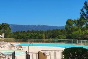 una piscina con sillas, árboles y una montaña en Mazet Castel in Pont-Royal en Mallemort