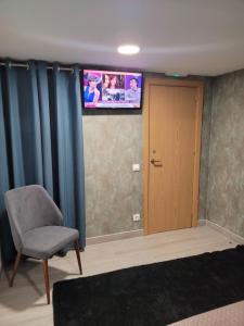 a room with a chair and a television on the wall at Hostal Bo Camiño in Porriño