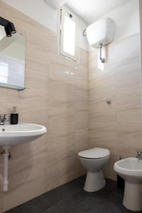 een badkamer met een wastafel, een toilet en een spiegel bij Dimora Flaminio in Peschici