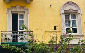 - un bâtiment jaune avec un balcon et deux fenêtres dans l'établissement 1881 Artistic Royal House, à Caserte