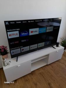 a flat screen tv sitting on a white tv stand at Appartement 'East' kortbij de zee in Ostend