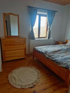 1 dormitorio con cama, tocador y espejo en Stone house (Каменната къща) en Leshten