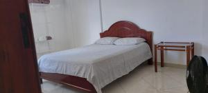 a bedroom with a bed with a white blanket and a table at Apartamento completo e bem localizado in Vitória da Conquista