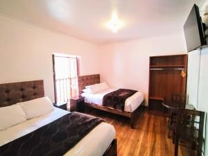 a hotel room with two beds and a window at Paqarina San Blas in Cusco