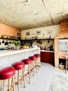um bar com bancos vermelhos numa cozinha em Casa de Poço Guest House and Gallery em Mindelo