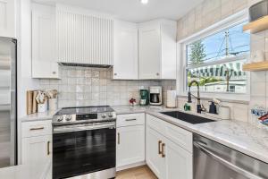 a kitchen with white cabinets and a sink and a window at Madeira Beach House Retreat with Private Pool - The Perfect Getaway! in St. Pete Beach