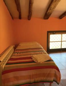 Cama en habitación con pared de color naranja en Cal Millo, en Vilella Alta