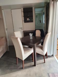 a dining room table and white chairs in a room at Mobil-Home camping 4**** LA MARINE in Le Grau-du-Roi