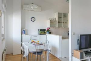 een kleine witte keuken met een tafel en een televisie bij Swanky Gem in Dubrovnik