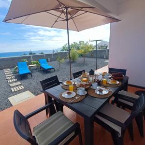 a table with food and an umbrella on a patio at Villa Bella Mar by Madeira Sun Travel in Porto Santo