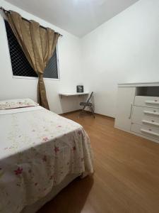 a bedroom with a bed and a dresser and a desk at Apartamento aconchegante em Betim in Betim