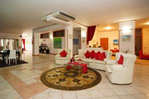 una sala de estar con muebles blancos y almohadas rojas. en RESIDENCE LUPIAE, en Lecce