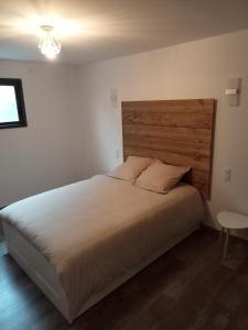 een slaapkamer met een groot bed met een houten hoofdeinde bij Le Dormadou des tilleuls in Graveson