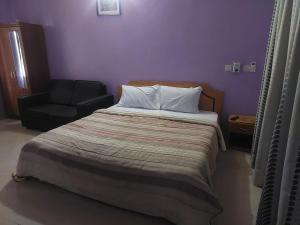 a bedroom with a large bed and a chair at NABTEL HOTEL in Spintex